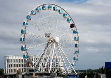 Mavi gondollu Skywheel dönme dolap bir rıhtımda bulutlu bir gökyüzü önünde dönüyor. Helsinki limanı Finlandiya