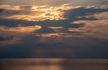 Sakin bir okyanusun üzerinde parlayan güneş, güneşin doğuşunda suyun üzerinde güzel bir altın yansıma yaratır.