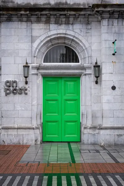 stock image Green painted wooden door of a post office building with an post sign in ireland