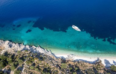 Turistlerin insansız hava aracı sahnesi, turkuaz suyla ıssız bir Yunan plajında güneşli bir yaz gününün tadını çıkarıyor. Turist teknesi kıyıya demir attı. İyon Denizi 'ndeki Kefalonia Yunan adası