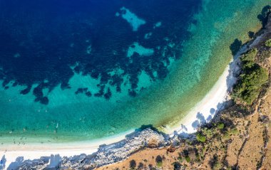 Turkuaz sular, turistlerin yaz aylarında güneşlendikleri ve yüzdükleri tenha bir plajda nazikçe tur atar. Tropik Kefalonya plajı Yunan adaları. Drone hava görüntüsü