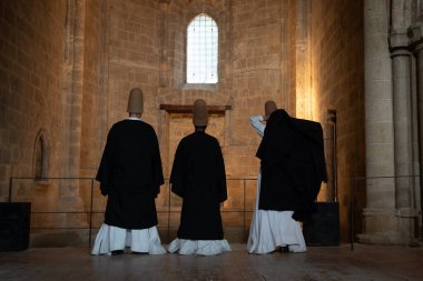 Three sufi dervishes wearing traditional clothes standing in bellapais abbey during a ceremony clipart