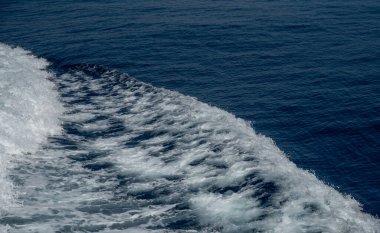 Beyaz deniz köpüğü, derin mavi suyun yüzeyinde bir girdap oluşturuyor.