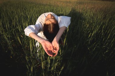 Yeşil çayır tarlasında dans eden beyaz elbiseli genç bir kadın. Dışarıda kaygısız bir kadın