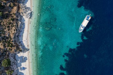 Turistlerin güneşli bir yaz gününün tadını çıkardıkları, turkuaz suyla ıssız bir Yunan plajının insansız hava aracı manzarası. Turist teknesi kıyıya demir attı. İyon Denizi 'ndeki Kefalonia Yunan adası