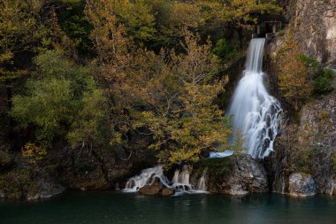 Sonbahar yapraklarıyla çevrili bir dağ nehrine dökülen su.