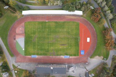 Yeşil bir futbol sahasını çevreleyen boş bir atletizm pistinin kuş bakışı görüntüsü spor müsabakalarına hazır.
