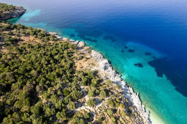 İyon denizindeki bir Yunan adasının kayalık kıyı şeridine çarpan inanılmaz turkuaz suyun insansız hava görüntüsü. Kefalonia, Yunanistan