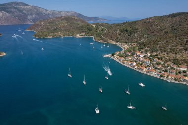 Güneşli bir yaz gününde, bir Yunan adası limanının turkuaz sularında yüzen yelkenlilerin hava manzarası. Vathi Ithaca, Yunanistan