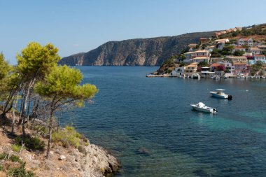 Kefonya, Yunanistan 'daki assos köyünün sakin manzarası. Renkli evleri, körfezde demirli tekneleri ve çam ağaçları var.