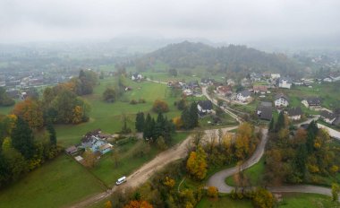 Drone Aerial view of houses in the countryside near a river surrounded by colorful autumn trees and fog, Podhom village radovna valley Slovenia clipart