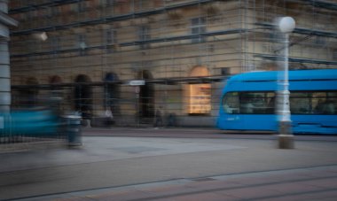 Şehir merkezinden geçen mavi tramvay hareket bulanıklığı etkisi hızı vurguluyor. Zagreb, Hırvatistan