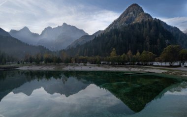 Beautiful landscape of mountains reflecting on jasna lake with autumn colors in kranjska gora, slovenia clipart