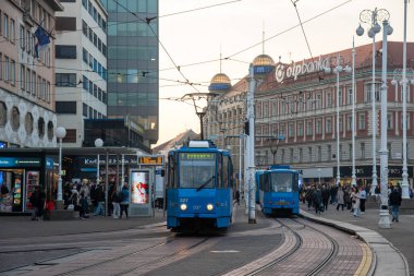 Zagrep, Coratia, 31 Ekim 2024: Bulutlu bir günde Hırvatistan 'ın zagreb kentindeki bir istasyonda modern bir tramvaya binen yolcular