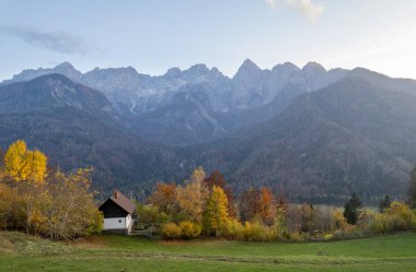 Büyüleyici evin insansız hava aracı manzarası arka planda görkemli Julian Alpleri ile canlı sonbahar yeşilliklerinin arasına yerleşmiş. Slovenya manzarası Slovenya