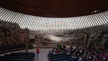 Helsinki, Finlandiya, 19 Temmuz 2024: Finlandiya 'nın başkenti Helsinki' de doğrudan kayaya oyulmuş temppeliaukio kilisesinin içindeki sıralarda oturan insanlar