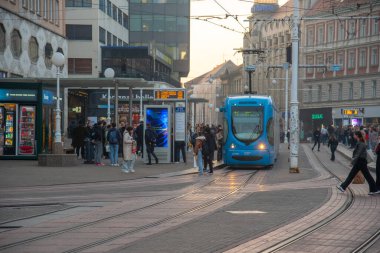 Zagrep, Coratia, 31 Ekim 2024: Bulutlu bir günde Hırvatistan 'ın zagreb kentindeki bir istasyonda modern bir tramvaya binen yolcular