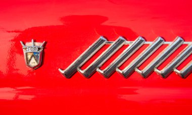 Bir Ford logosunun yakın görüntüsü ve klasik kırmızı bir arabanın dekoratif süslemesi, gösterişli otomotiv tasarımı