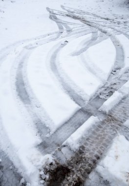 Araba lastiği kışın kar ve buzla kaplı bir yolda kıvrılıyor.