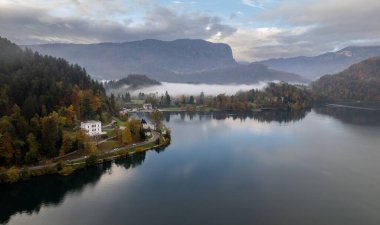 Göz kamaştırıcı göl manzarası rengarenk sonbahar yaprakları ve arka plandaki dağları kaplayan alçak sis ile kanadı.