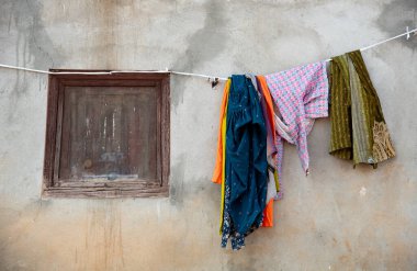 Kırsal pencereli yıpranmış bir duvara asılmış basit bir çamaşır ipinde havanın kuruması günlük hayatın bir duygusunu uyandırıyor.