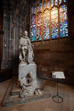Manchester, İngiltere - 16 Temmuz 2019 Humphrey Chetham 'ın heykeli ve Manchester Katedrali' nin içindeki renkli cam pencere.