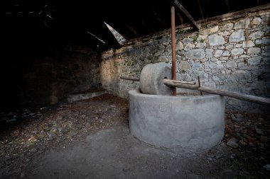 Eski değirmen taşı, zamanın ve çürümenin geçişini gösteren çökmüş taş duvarlı karanlık ve terk edilmiş bir binada oturuyor.