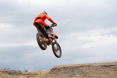 Motosikletli sporcu motosikletle dışarıda motosiklet yarışı yapıyor.