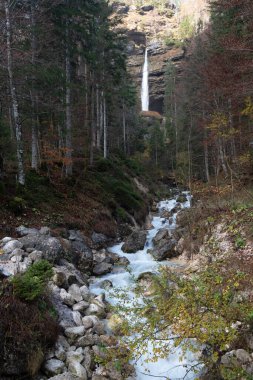 Vadide şelale akıyor. Turkuaz su kayalık bir nehir yatağından akar. Slovenya. Triglav Bistrica Şelalesi