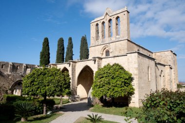 Kuzeydeki Bellapais Manastırı güneşli bir günde yıpranmış taş duvarlarını ve kemerlerini sergiler.
