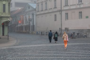 Ljubljana, Slovenya, 31 Ekim 2024: Sisli şehir merkezinde yürüyen turistler, Ljubljana, Slovenia, Avrupa