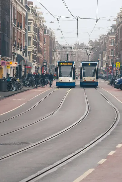 Amsterdam Hollanda, 9 Şubat 2025: Sisli bir günde Amsterdam şehir merkezindeki merkez istasyona doğru giden iki modern tramvay