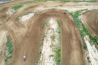 Motokros yarışçılarının toprak yolda uçarak dinamik ve heyecan verici bir motor sporu yarışması sahnesi yaratmaları.