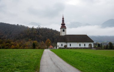 Bitnje 'deki düşük bulutlu marijinega vnebozetja kilisesi renkli bir sonbahar ormanına yerleşerek sakin ve resimsel bir manzara yaratıyor. Slovenya kırsal kesimi