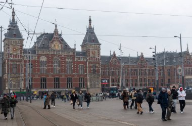 Amsterdam, Hollanda, 9 Şubat 2025: Hollanda 'nın kuzeyindeki Amsterdam Centraal İstasyonu önünde turistler ve yerliler yürüyor ve gidip geliyorlar