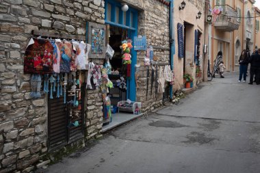 Lefkara, Kıbrıs, 28 Aralık 2024: Alışılagelmiş el yapımı hediyelik eşya dükkanının dışında büyüleyici bir taş sokakta taş duvarlı. Lefkara Köyü Kiril
