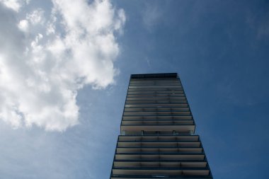 Modern gökdelen mavi gökyüzüne uzanıyor, çağdaş mimari ve kentsel gelişimi sergiliyor