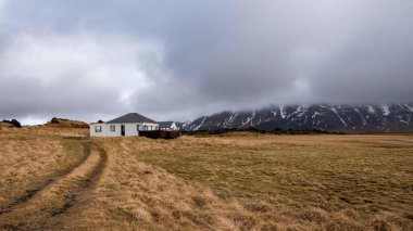 Kışın İzlanda manzarası. Çiftlik evi, pansiyon, yazlık ev, dağ evi, bulutlu gökyüzü. İzlanda Avrupa