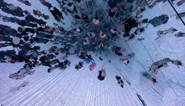 Ayna gibi bir ışıkla yürüyen turistler büyüleyici ve fütüristik bir atmosfer yaratıyor.