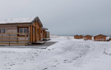 Ahşap tatil kulübeleri kışın donmuş topraklar ve kıyılar. İzlanda manzarası İzlanda