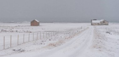 Karla kaplı yol İzlanda 'da terk edilmiş bir çiftliğe çıkıyor. Kar fırtınası yaklaşıyor. Donmuş yol İzlanda