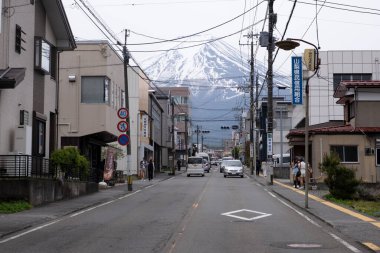Fujiyama, Japonya, 24 Nisan 2025: Dükkanları ve sokak lambaları ile geleneksel Japon caddesi görkemli Fuji Dağı 'na doğru yol alıyor ve güzel bir manzara yaratıyor. Fujiyama Japonya Asya