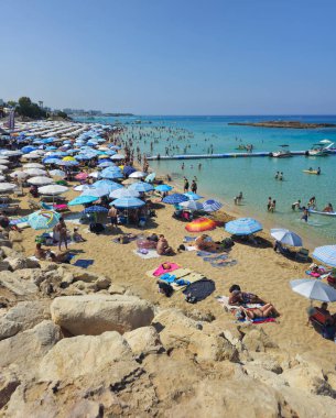 PROTARAS, CYPRUS, 8 Haziran 2025: İncir Ağacı 'nın ünlü sahil sahilinde turistler, Kıbrıs' taki Protaras tatil beldesinde tatil yapıyorlar. Sandy egzotik plajı