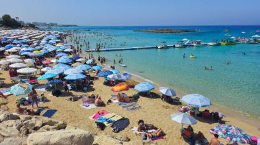 PROTARAS, CYPRUS, 8 Haziran 2025: İncir Ağacı 'nın ünlü sahil sahilinde turistler, Kıbrıs' taki Protaras tatil beldesinde tatil yapıyorlar. Sandy egzotik plajı