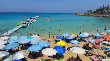 PROTARAS, CYPRUS, 8 Haziran 2025: İncir Ağacı 'nın ünlü sahil sahilinde turistler, Kıbrıs' taki Protaras tatil beldesinde tatil yapıyorlar. Sandy egzotik plajı