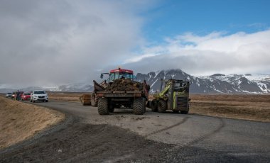 Snaefellsness, İzlanda, 20 Mart 2016: Gübre yüklü traktör İzlanda 'da bir yolu tıkıyor, bir forklift ve arabalar bekliyor, ve uzaktaki karlı dağlar