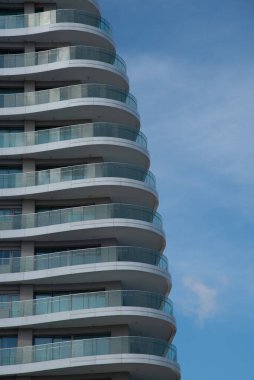 Tekrarlanan balkonlar ve pencereler modern bir bina cephesinde büyüleyici bir desen oluşturur.