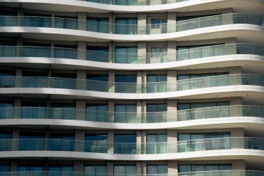 Tekrarlanan balkonlar ve pencereler modern bir bina cephesinde büyüleyici bir desen oluşturur.