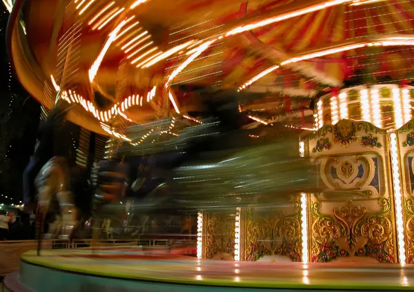 Dönen bir atlıkarıncanın parlak çizgileri, panayırdaki bir gecenin enerjisini ve heyecanını yakalıyor.