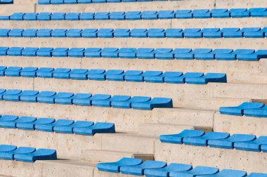Beton stadyum tribünlerinde boş mavi koltuklar.